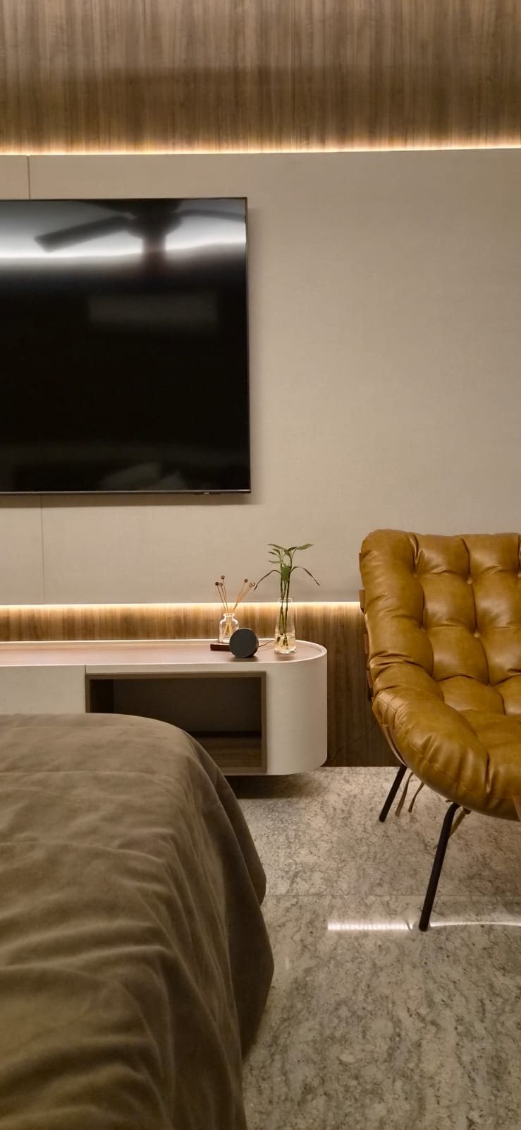 Quarto com painel ripado e poltrona de couro